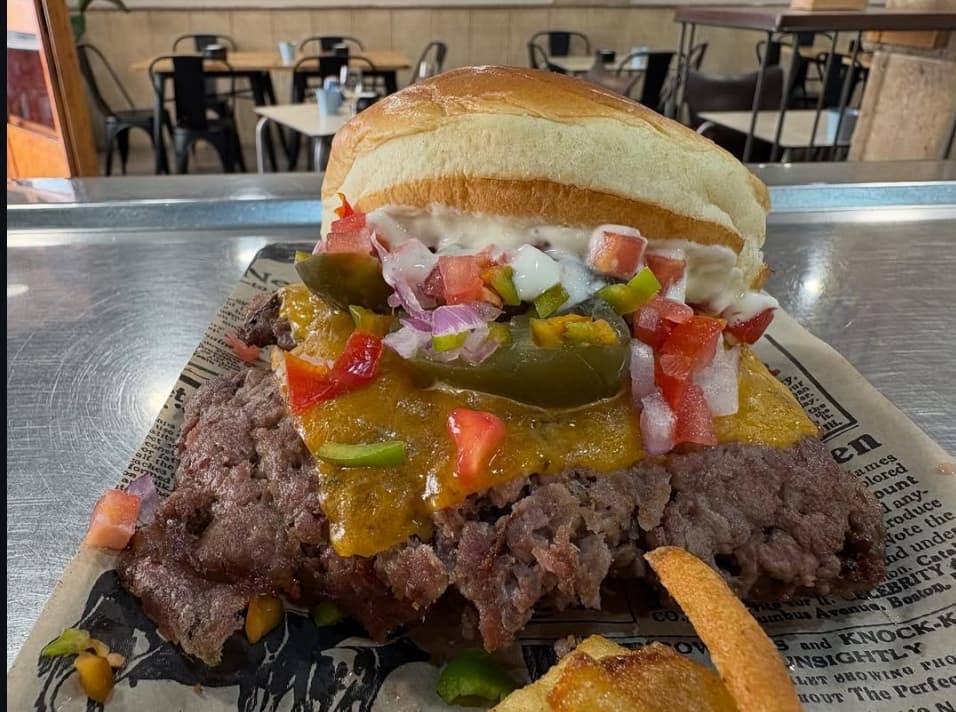Hamburguesa con carne abundante, queso fundido, pico de gallo y jalapeños en pan brioche.